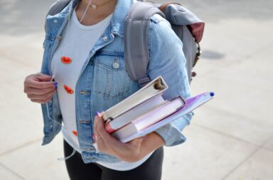 A student on their way to class, holding their books, and listening to music.
